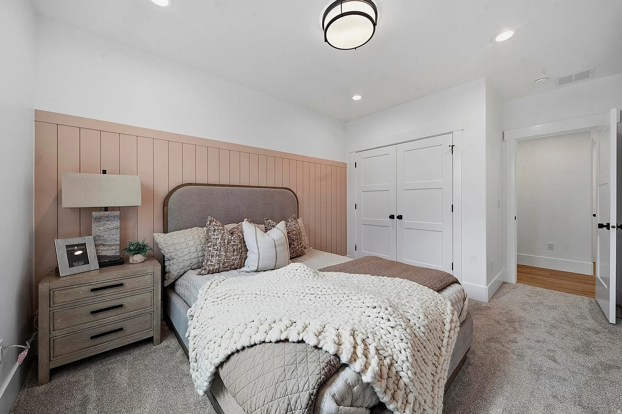 An Eagle Point Homes bedroom with a paneled accent wall and neutral furnishings