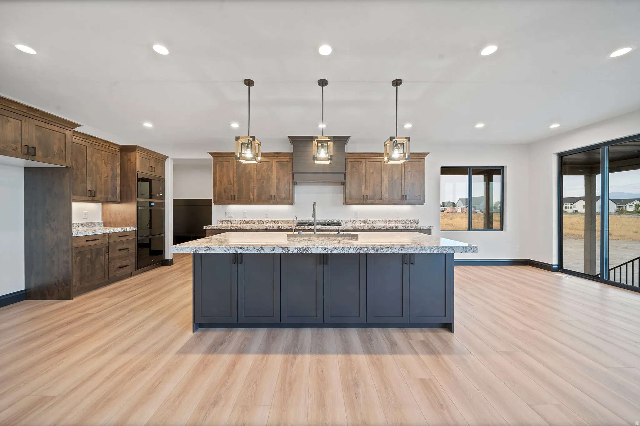 An Eagle Point Homes kitchen with a dark island, pendant lights, and custom wood cabinetry