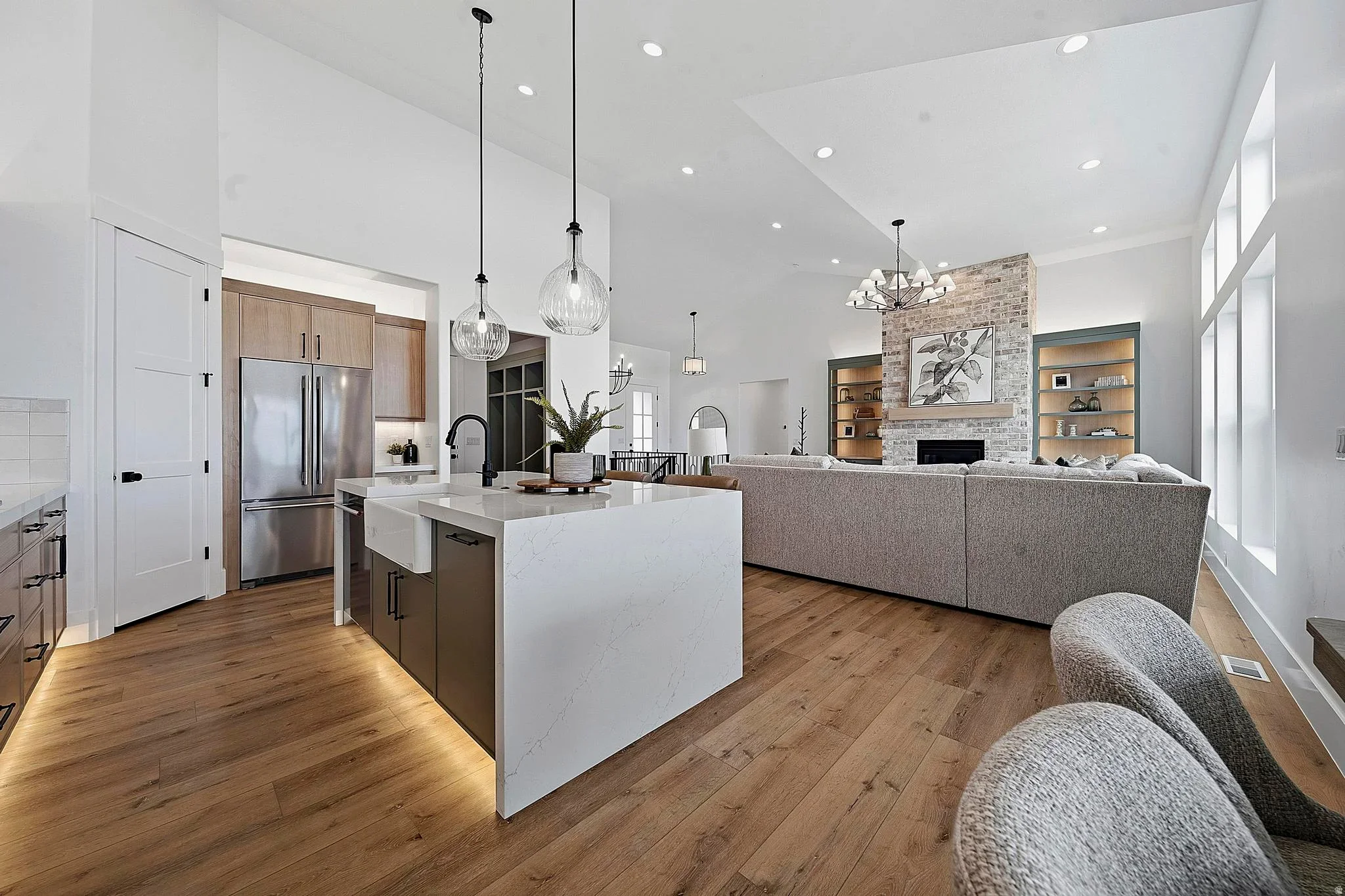 An Eagle Point Homes kitchen with wood cabinetry, a large island, and a stone fireplace beyond